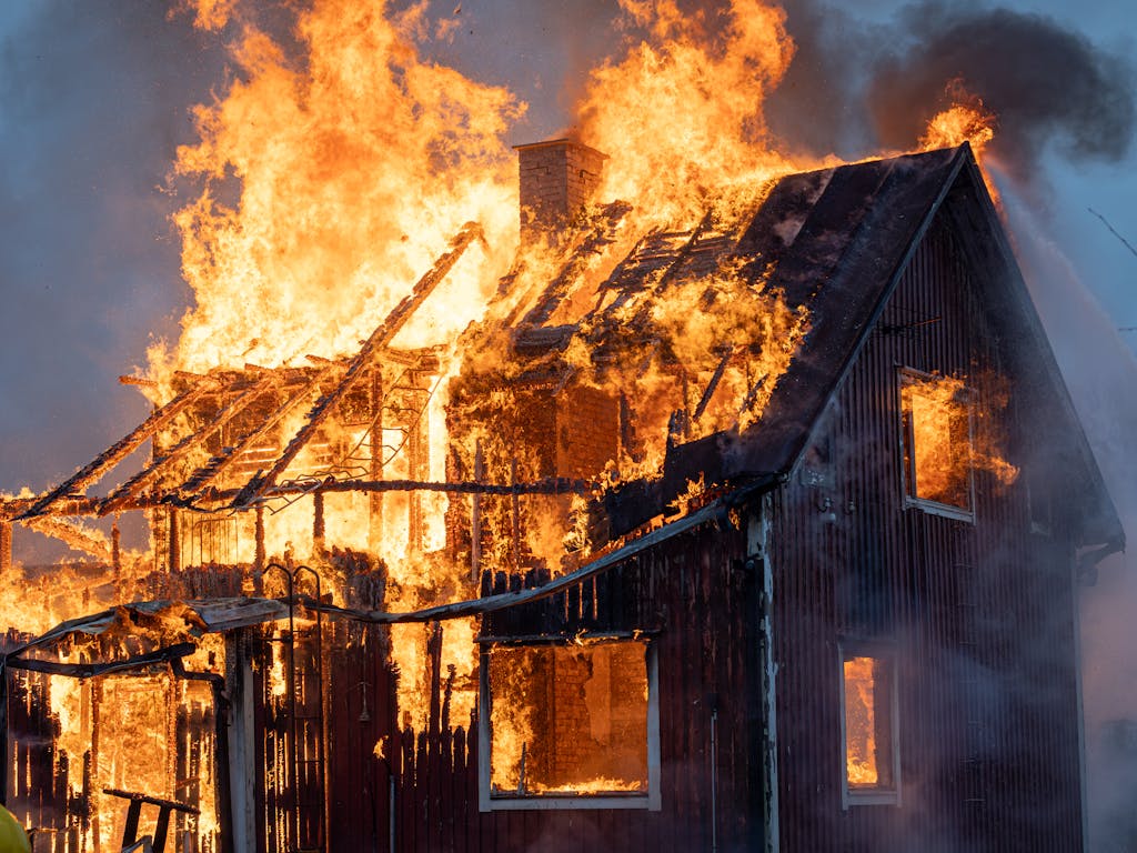 A house consumed by intense flames and smoke, capturing the power of fire.