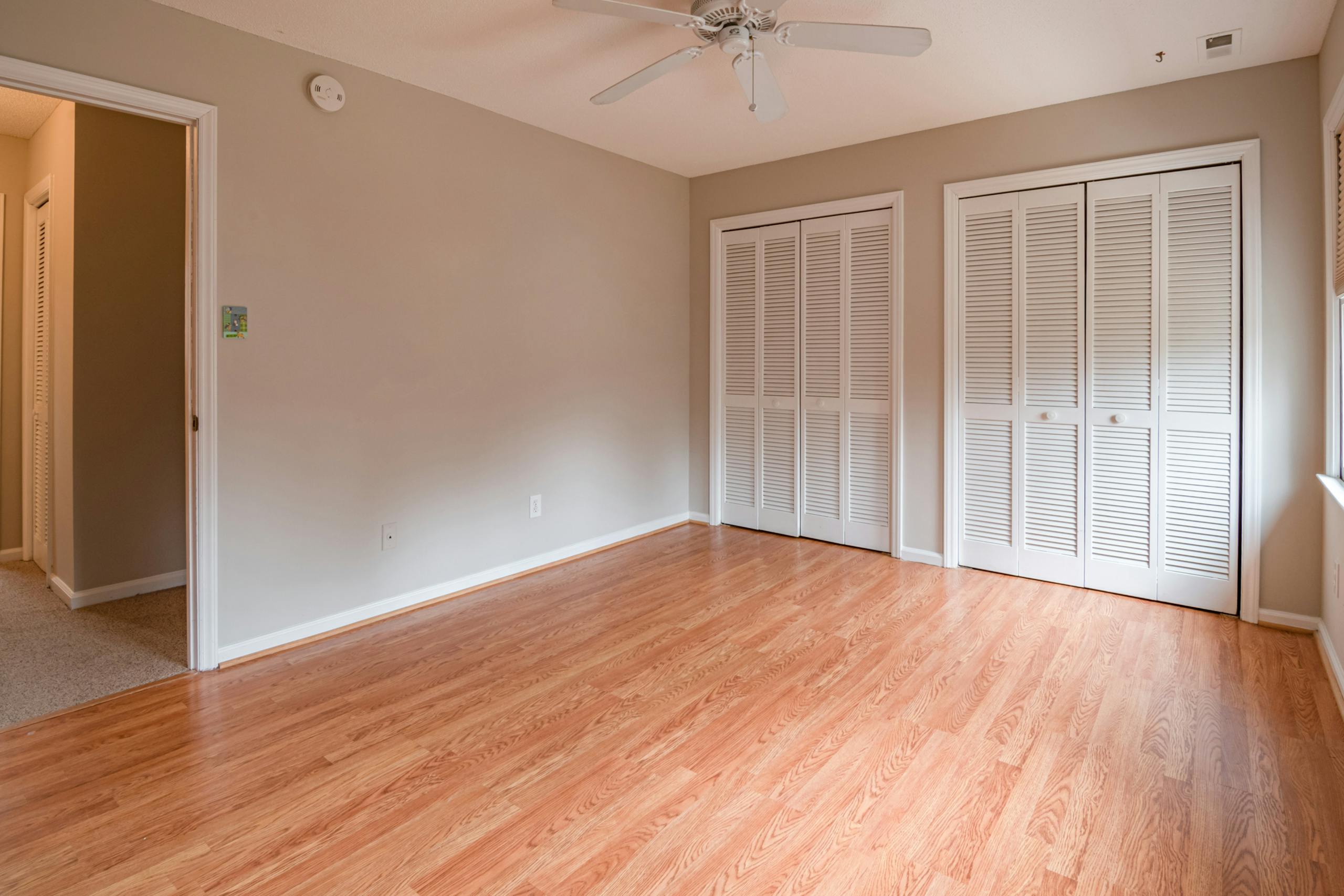 Bright empty room with hardwood floors and closet space, ideal for various design choices.